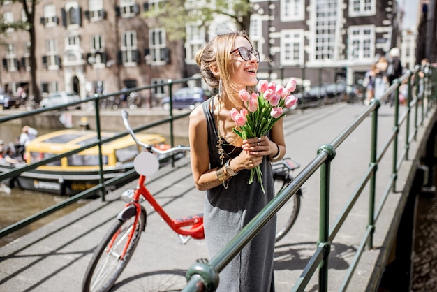 Portrait d'une belle jeune femme debout avec bouguet de tulipes roses sur le pont dans la vieille ville d'Amsterdam