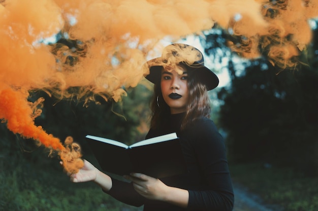 Photo portrait d'une belle jeune femme debout avec un livre au milieu des arbres