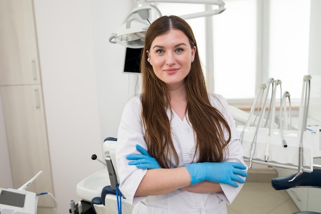 Portrait d'une belle jeune femme dentiste qui est dans son cabinet dentaire