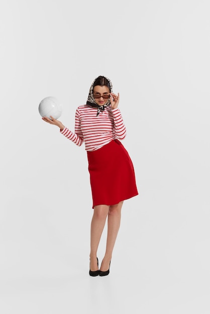 Portrait d'une belle jeune femme élégante en chemise rayée posant avec un ballon de volley-ball isolé sur