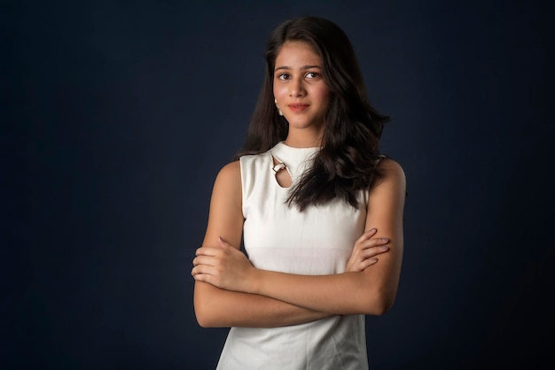 Portrait d'une belle jeune femme émotionnelle souriante posant avec les mains jointes sur fond gris