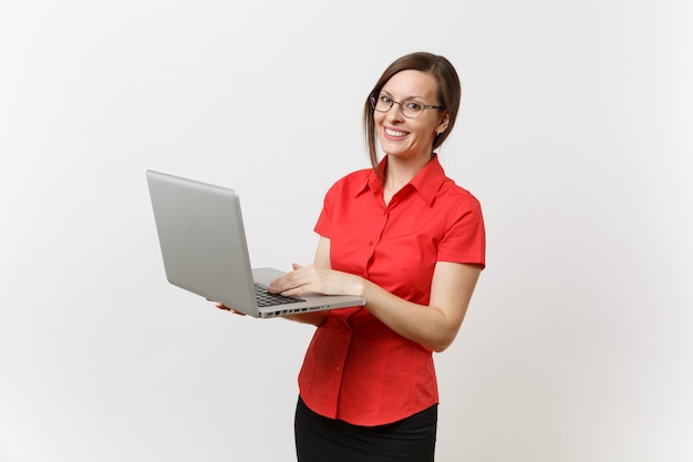 Portrait d'une belle jeune femme enseignante d'affaires en chemise rouge, lunettes travaillant en tapant sur un ordinateur portable isolé sur fond blanc. Éducation ou enseignement dans le concept d'université de lycée