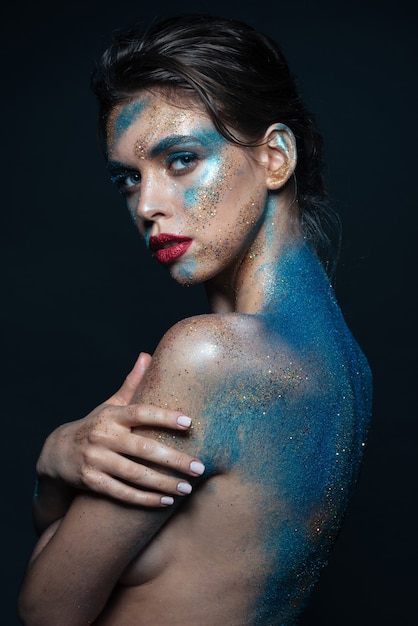 Portrait de belle jeune femme avec des étincelles bleues sur son corps sur fond noir