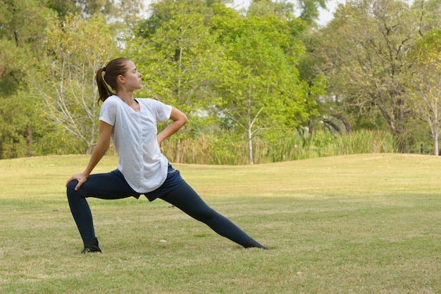 Portrait de la belle jeune femme exerçant dans le parc en plein air