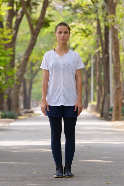 Portrait de la belle jeune femme exerçant dans le parc en plein air