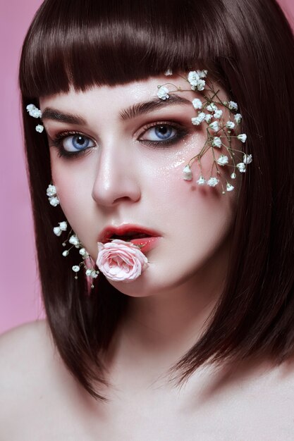 Portrait de la belle jeune femme avec des fleurs sur son visage. maquillage de style coréen, beauté de poupée