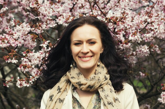 Portrait d'une belle jeune femme sur fond de cerisiers roses au printemps