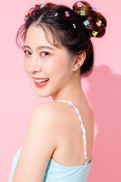 Portrait de la belle jeune femme heureuse asiatique en robe de mode mignonne bleue porter des lunettes de soleil souriant et posant sur un espace vide de fond de couleur rose pastel isolé