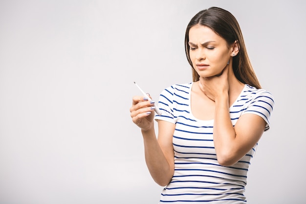 Portrait d'une belle jeune femme inquiète vérifiant sa température