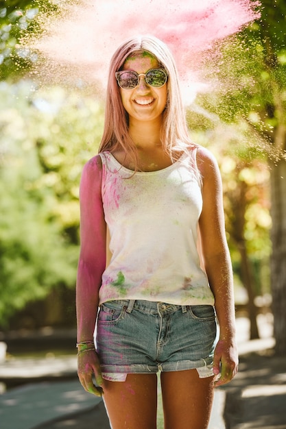 Portrait de la belle jeune femme jouant dans le parc sur le festival des couleurs holi.