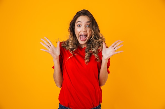 Portrait d'une belle jeune femme joyeuse debout isolée sur un mur jaune, célébrant le succès