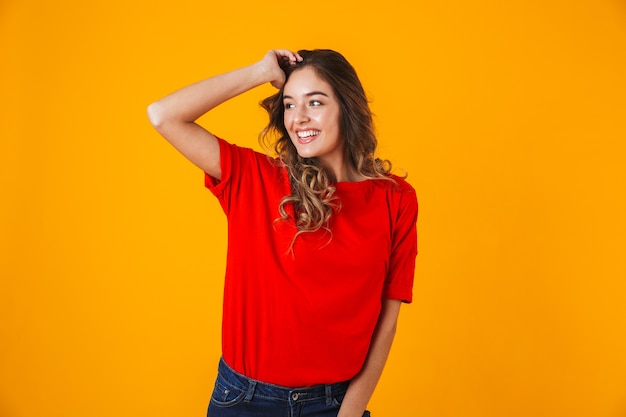 Portrait d'une belle jeune femme joyeuse et ludique debout isolée sur un mur jaune, posant