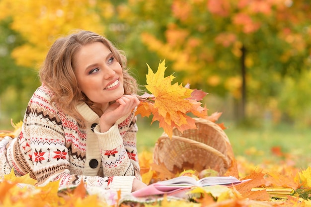 Portrait de la belle jeune femme lisant dans le parc