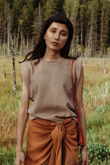 Portrait d'une belle jeune femme métisse avec de la peinture pour le visage ethnique dans une forêt marécageuse