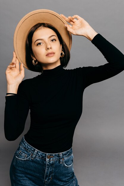 Portrait d'une belle jeune femme à la mode en costume de corps noir et chapeau. Photo de haute qualité