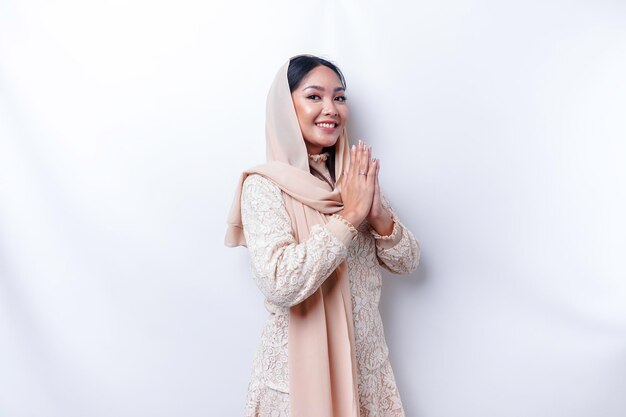 Portrait d'une belle jeune femme musulmane asiatique portant un hijab gesticulant Eid Mubarak salutation