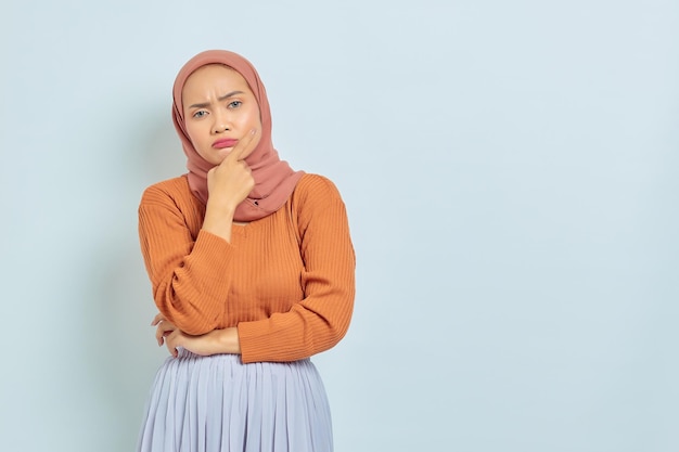 Portrait de la belle jeune femme musulmane asiatique en pull marron et regardant sérieusement la question et regardant la caméra isolée sur fond blanc Concept de mode de vie musulman