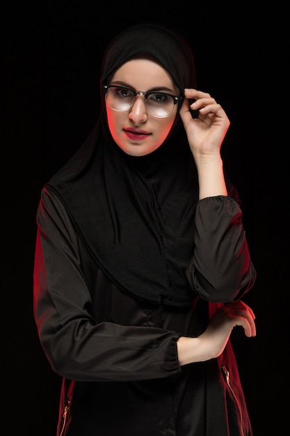 Portrait de la belle jeune femme musulmane branchée portant un hijab noir et des lunettes en tant que concept de mode orientale moderne posant sur un t-shirt noir