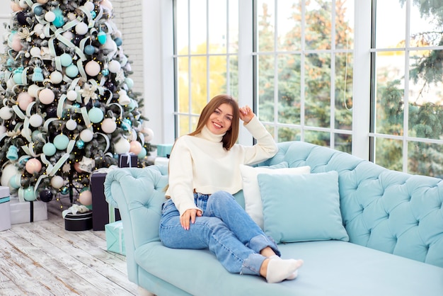 portrait de belle jeune femme à noël à la maison sur canapé