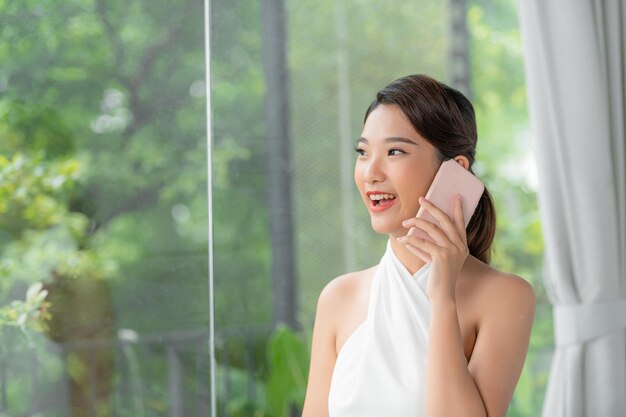 Portrait d'une belle jeune femme parlant au téléphone à la maison