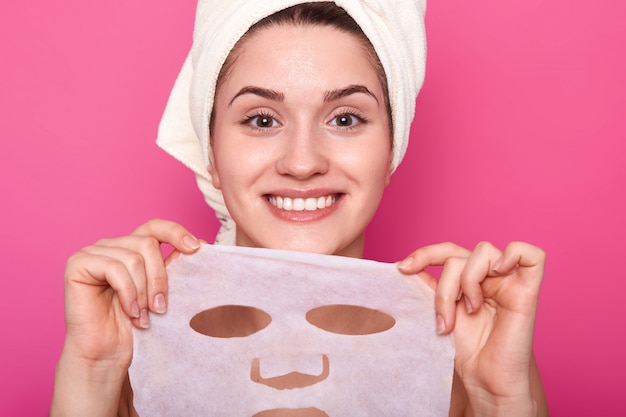 Portrait de la belle jeune femme avec une peau parfaite mettant un masque facial nourrissant, le temps des procédures de spa, semble heureux et détendu