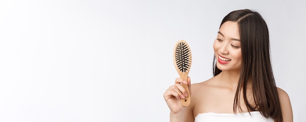 Portrait d'une belle jeune femme peigne cheveux magnifiques isolé sur fond blanc beauté asiatique