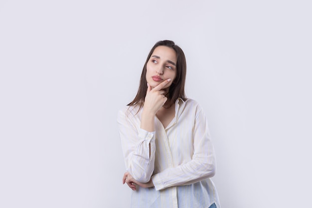 Portrait d'une belle jeune femme pensant isolé sur fond blanc