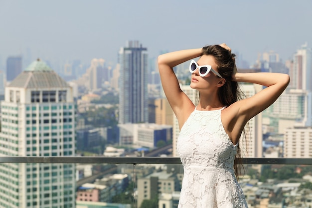 Portrait de la belle jeune femme portant des lunettes de soleil dans la grande ville moderne