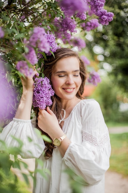 Portrait d'une belle jeune femme près du lilas en fleurs. Printemps.