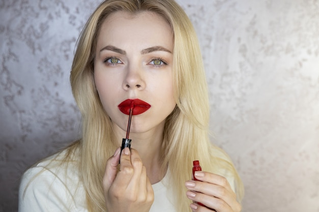 Portrait d'une belle jeune femme qui fait du maquillage avec des lèvres rouge vif