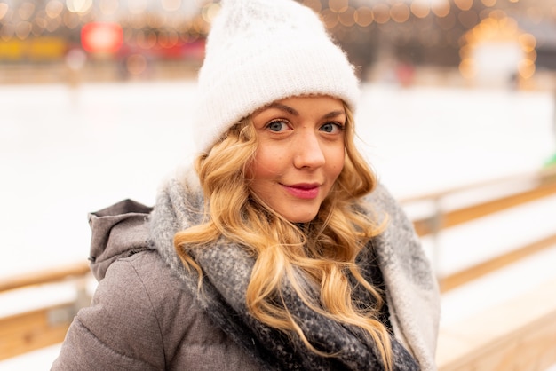 Portrait de la belle jeune femme sur le rang de glace de Noël festif. Dame portant des vêtements tricotés chauds d'hiver.