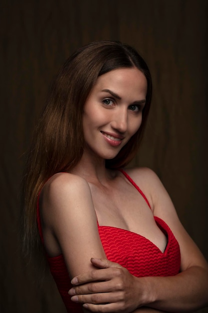 Portrait d'une belle jeune femme en robe rouge tourné en studio sur un fond sombre