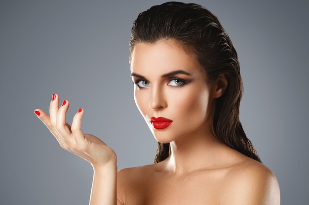 Portrait de la belle jeune femme avec un rouge à lèvres et du vernis à ongles