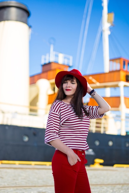 Portrait de belle jeune femme en rouge posant sur grand yacht vintage