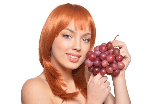 Portrait de belle jeune femme rousse avec des raisins rouges