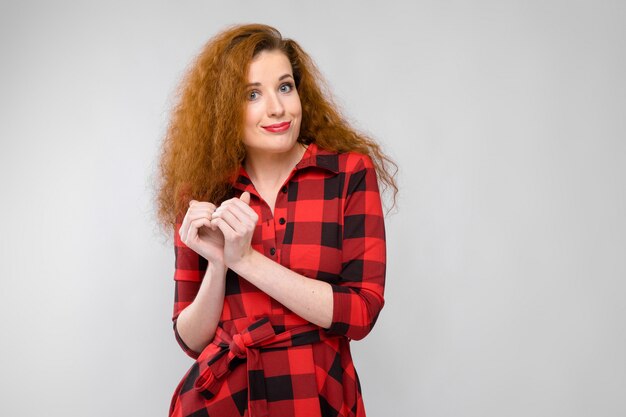 Portrait de belle jeune femme rousse souriante montrant le signe de l'amour