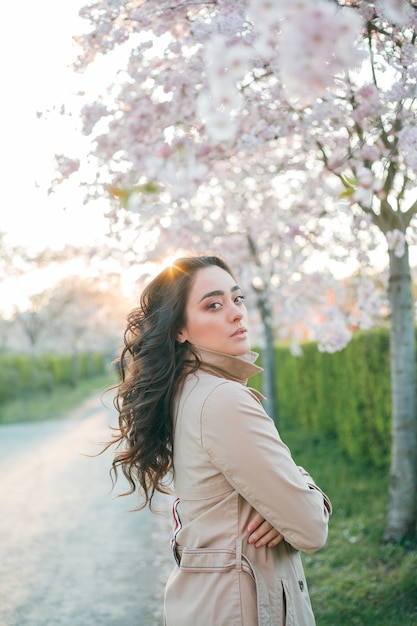 Portrait d'une belle jeune femme en sakura en fleurs au coucher du soleil