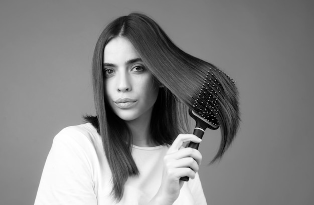 Portrait d'une belle jeune femme se peignant les cheveux en souriant Une femme se peinant les cheveux en bonne santé avec un peigne