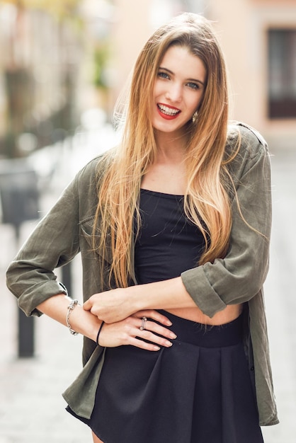 Portrait d'une belle jeune femme souriante debout sur le trottoir