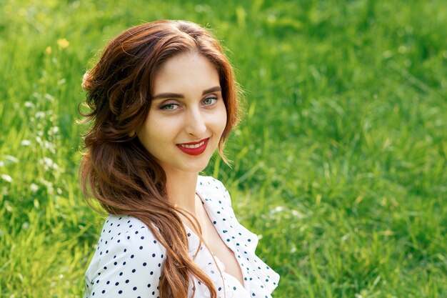 Portrait de la belle jeune femme souriante sur fond vert de la nature estivale.