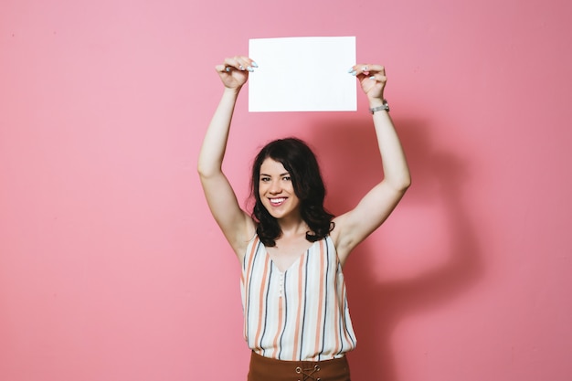 Portrait de la belle jeune femme souriante et tenant une feuille de papier vierge