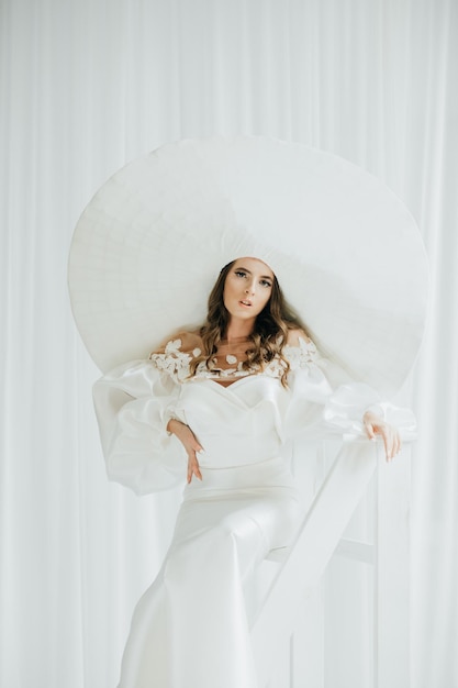 Portrait d'une belle jeune femme de style rétro dans un élégant chapeau blanc et une robe