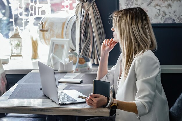 portrait d'une belle jeune femme travaillant en ligne dans un café sur un ordinateur portable