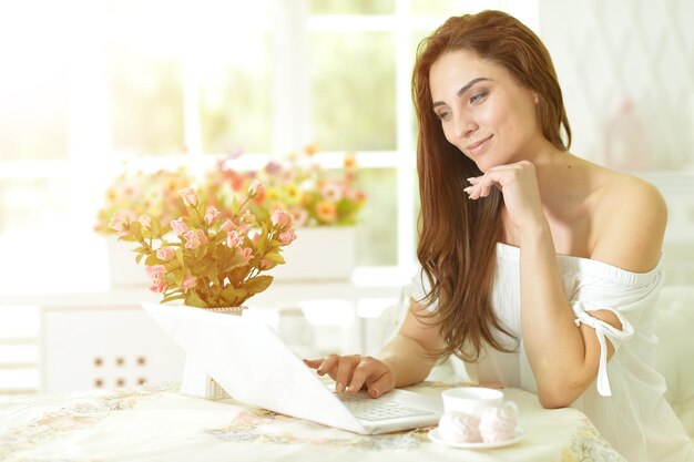 Portrait d'une belle jeune femme utilisant un ordinateur portable à l'intérieur