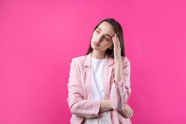 Portrait de la belle jeune femme en veste rose pensant isolé sur fond rouge