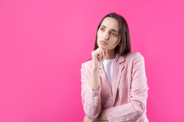 Portrait de la belle jeune femme en veste rose pensant isolé sur fond rouge