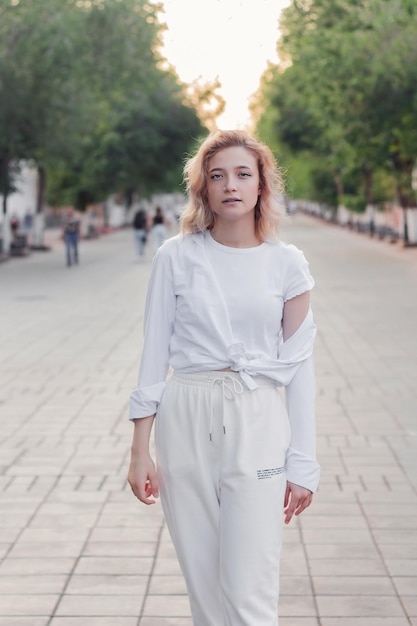 Portrait d'une belle jeune femme en vêtements blancs sur l'allée de la ville