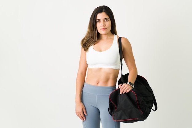 Portrait d'une belle jeune femme en vêtements de sport arrivant pour faire des exercices d'entraînement avec un sac de sport