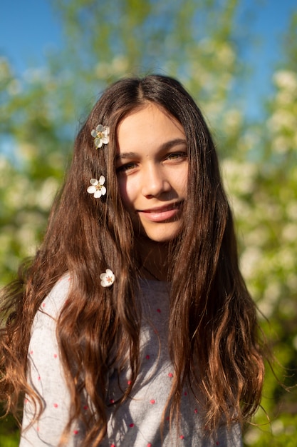 Portrait d'une belle jeune fille adolescente dans un jardin en fleurs au printemps vert