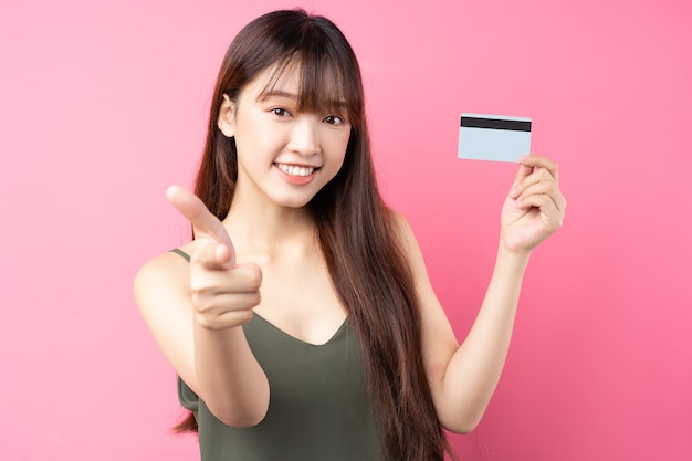 Portrait d'une belle jeune fille asiatique posant sur un mur rose